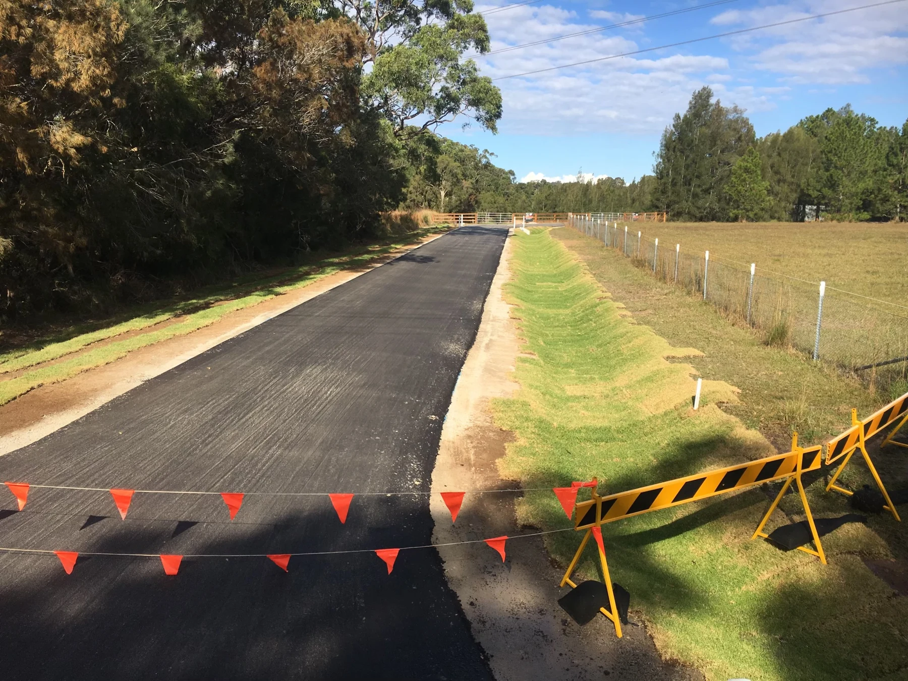 Surfaced rural access road bordered by grass
