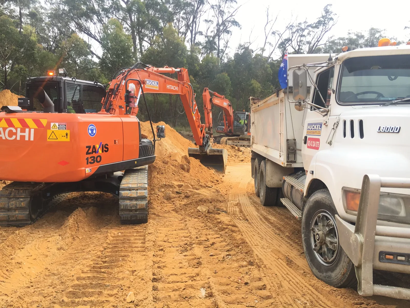 Two Huckel excavators working beside a tipper truck on an earthmoving site