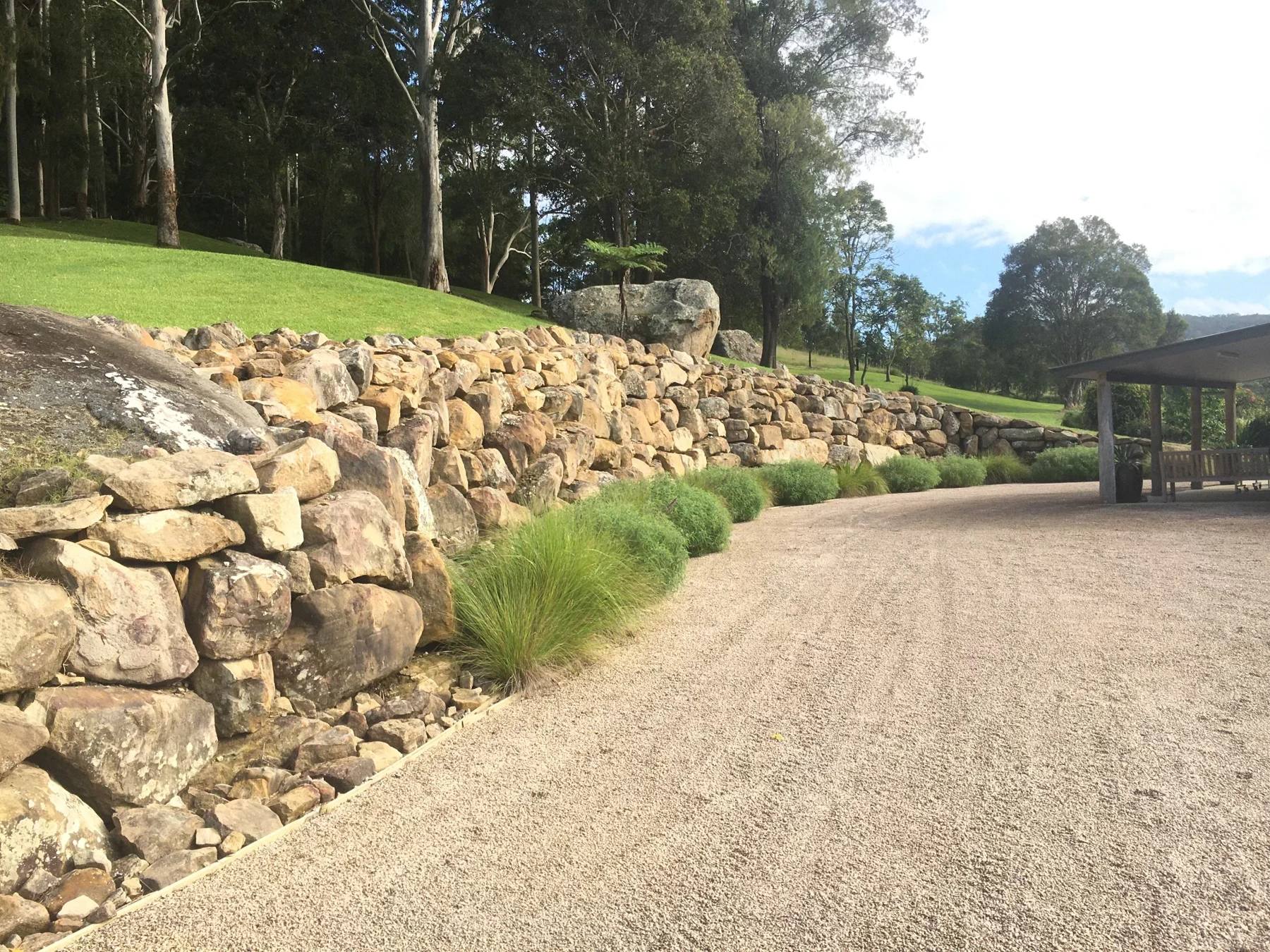 Sandstone retaining wall beside a rural driveway